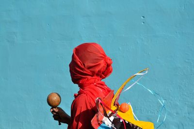 Side view of woman covered with scarf against wall