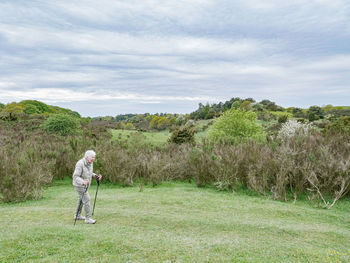 Woman in a natural park in denmark is hiking with hiking sticks