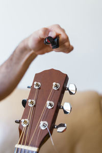 Cropped hand of man preparing guitar in home