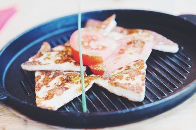 Close-up of halloumi and tomato slice in sauce pan on table