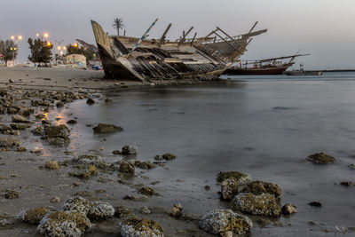 Abandoned boat in water against sky