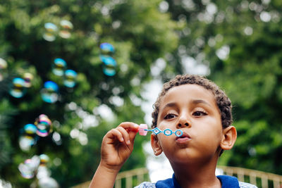 Boy blowing bubbles in park