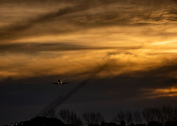 Low angle view of silhouette airplane against sky during sunset