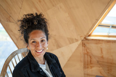 Happy latin woman smiling while sitting indoors.