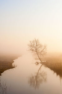 Scenic view of lake against sky during foggy weather