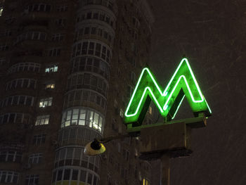 Neon sign of the subway at night on the background of a residential building in kiev