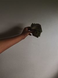 Close-up of hand holding umbrella over white background