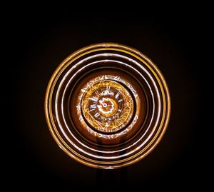 Close-up of illuminated light bulb against black background