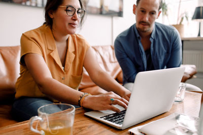 Businesswoman typing on laptop while discussing with male colleague in office