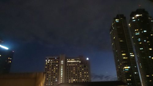 Low angle view of illuminated buildings against sky at night