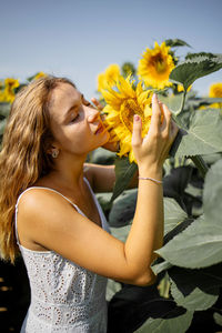 Beautiful blonde girl posing with sun flowers in summer