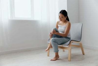 Side view of young woman sitting on floor at home