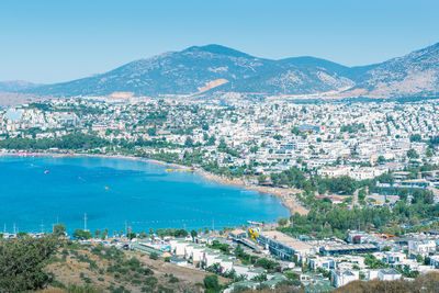 High angle view of city by sea against blue sky