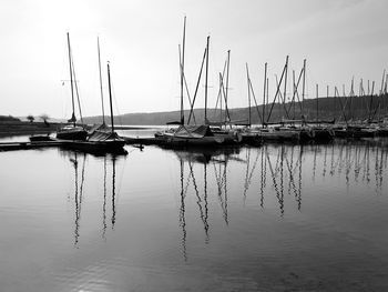 Sailboats moored in lake against sky