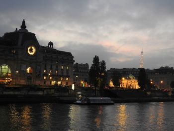 River with illuminated buildings in background at sunset