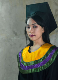 Portrait of a beautiful young woman standing against wall