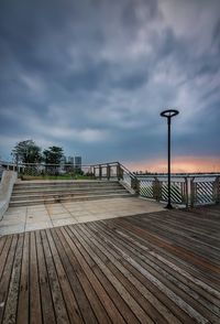 Empty footpath by railing against sky