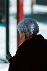 Rear view of senior woman using mobile phone