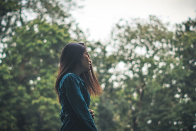 Side view of woman standing against trees