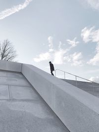 Man on staircase against sky