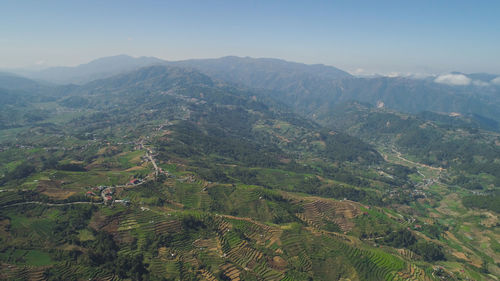 Aerial view of rice terraces and agricultural farm land on the slopes of mountains valley. 