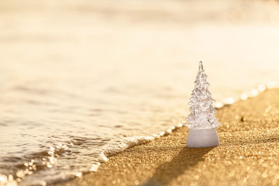 Christmas tree glass decoration on the beach on a golden beach. christmas and winter holyday concept