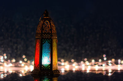 Lantern with lights decorating for islamic new year put at window with rain drop at background.