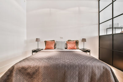 Rear view of man sleeping on bed against wall