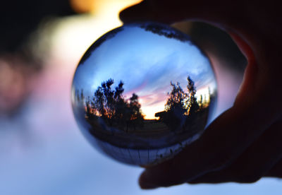 Close-up of hand holding ball against sky