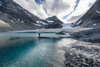 Rear view of hiker standing on rocks amidst river