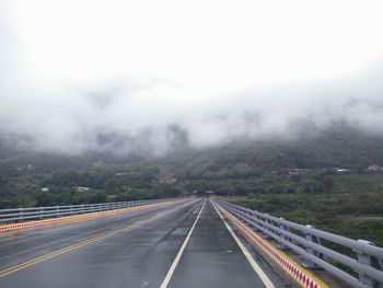 Road leading towards mountain against sky