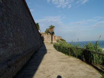 Walkway by building against sky