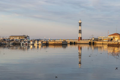 The port of cattolica with the boats and the lighthouse reflecting in the water at sunset