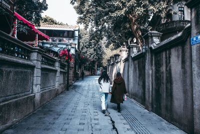Rear view of women walking on street in city