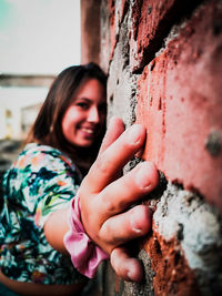 Close-up portrait of smiling young woman against wall