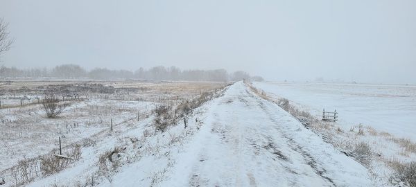 Snow covered land against clear sky