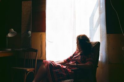 Side view of woman sitting at home