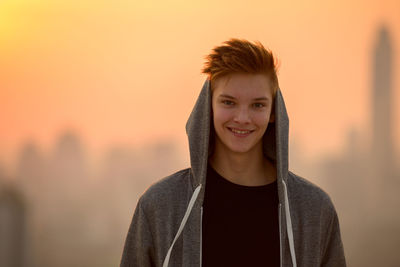 Portrait of smiling woman standing against orange sky