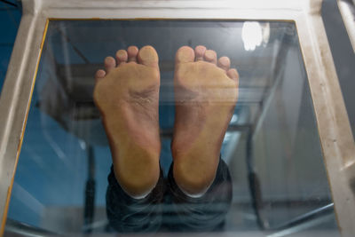 Low section of man standing on glass