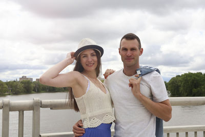 Portrait of young couple standing against railing