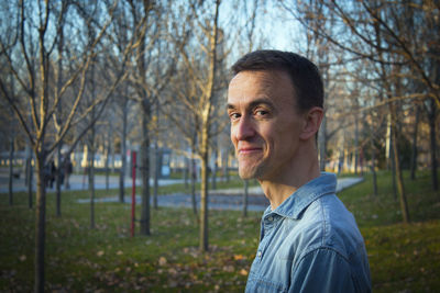 Portrait of young man standing against trees