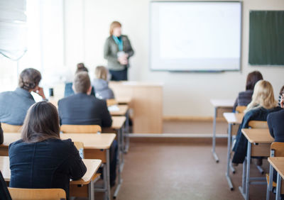 Rear view of students sitting in classroom