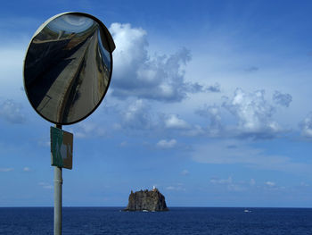 Road mirror by sea against sky