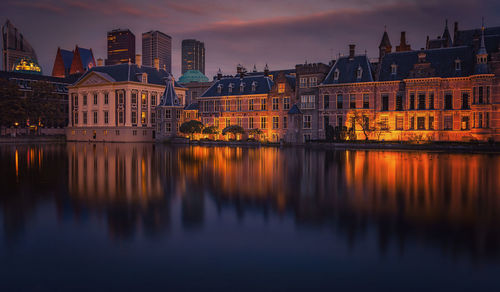 Reflection of illuminated buildings in river at sunset