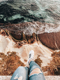 Low section of person on rock by sea