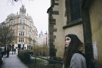 Portrait of woman standing by buildings in city