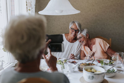 Senior women having picture taken while having meal together