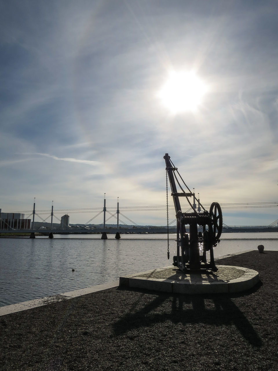 water, sky, sea, nautical vessel, sun, sunlight, cloud - sky, transportation, mode of transport, harbor, crane - construction machinery, commercial dock, sunbeam, silhouette, built structure, outdoors, nature, pier, boat, beach