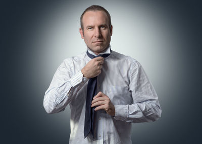 Portrait of businessman getting dressed against gray background