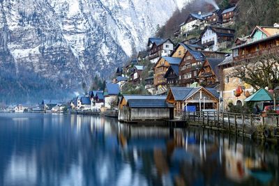 Houses by lake against snowcapped mountains during winter